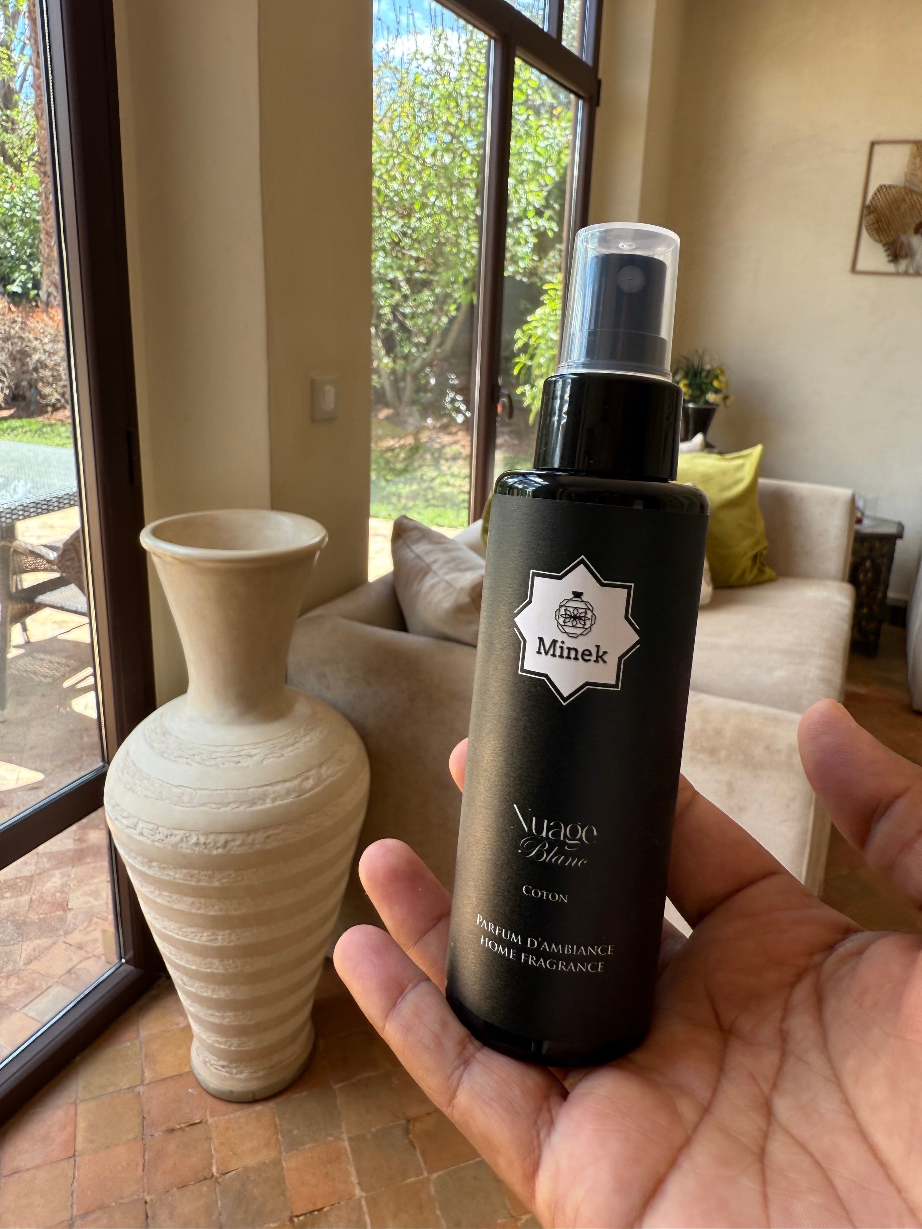 Salon élégant et lumineux avec diffuseur parfumé sur table basse, évoquant une ambiance d’hôtel de luxe