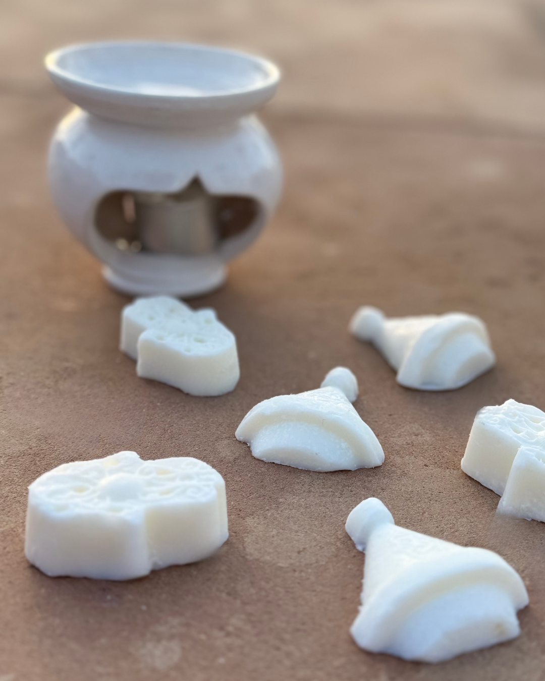 Galets de cire parfumée Mïnek en forme de tajine et de khmissa devant un brûle-parfum en céramique